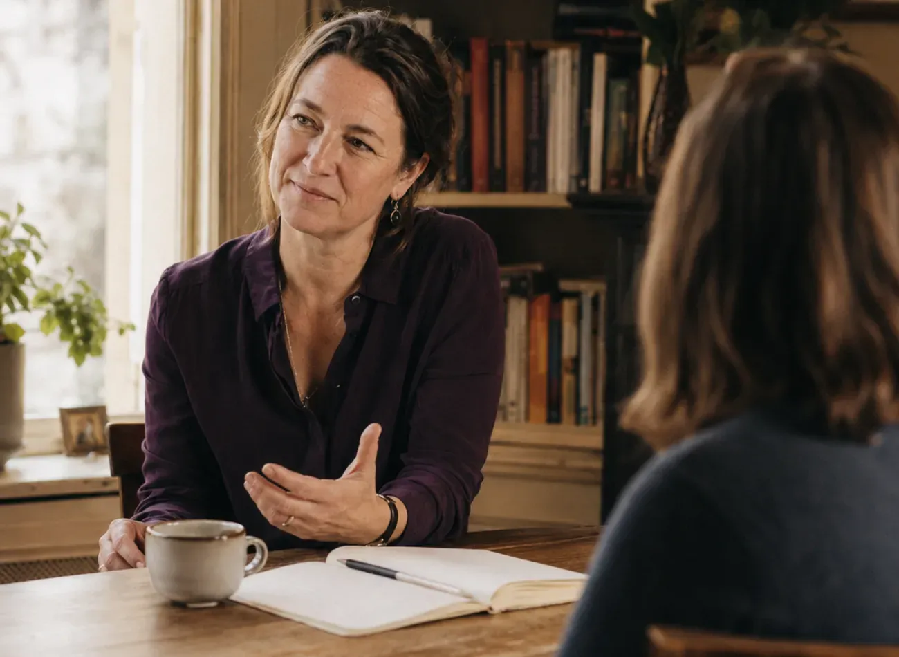 In gesprek aan de houten tafel, met notitieboek en thee