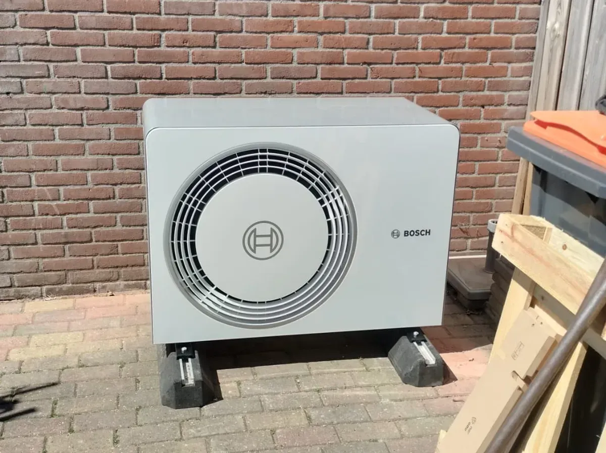 Geplaatste warmtepomp-buitenunit naast de bakstenen gevel